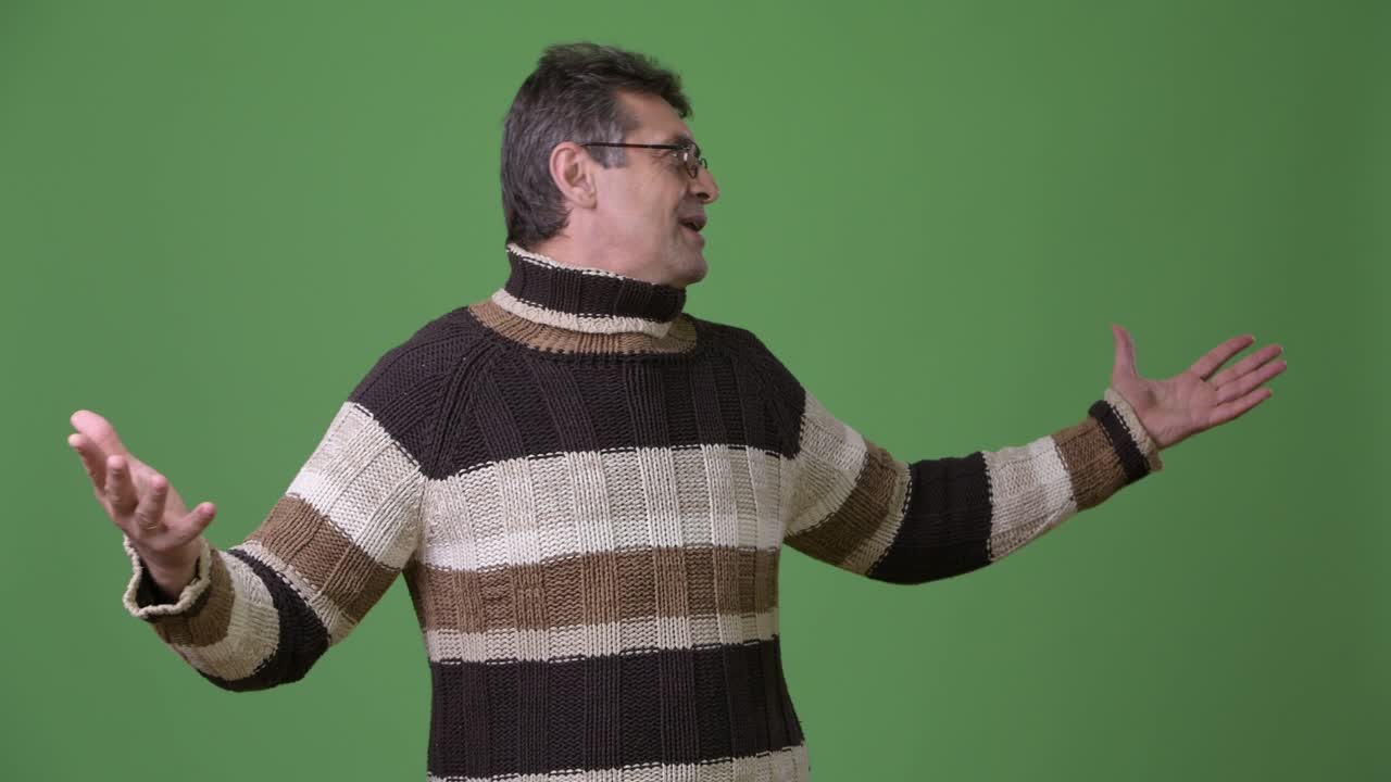 초록색 배경 에 털 목 스웨터 를 입은 성숙 한 잘생긴 남자