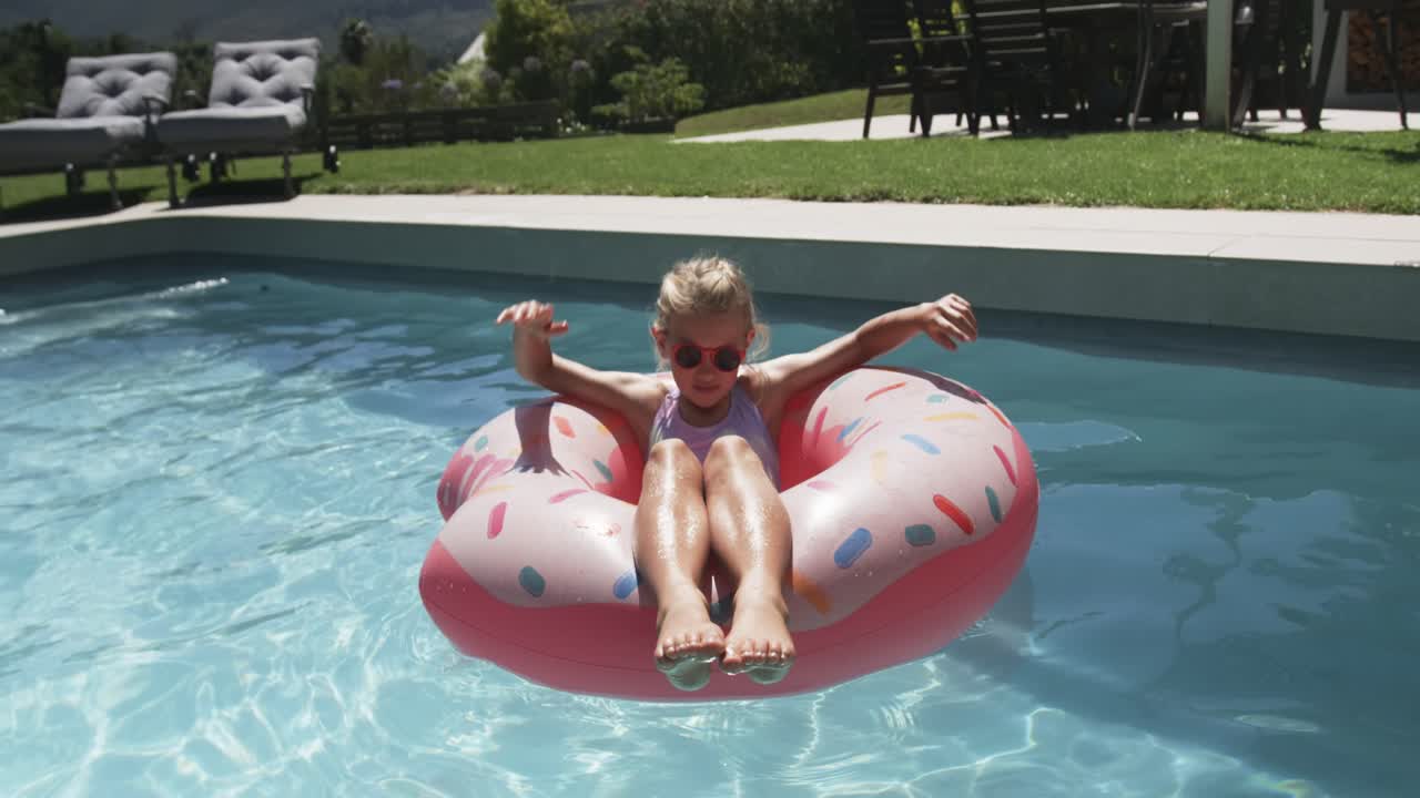 Youth female in swimsuit shades adjusting,reclining on donut float in backyard pool sun urging rest
