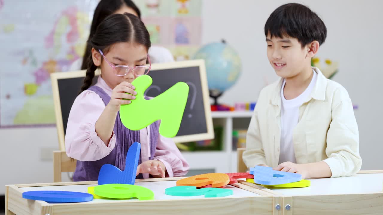 Two young Asian students interact with colorful foam numbers during a ...