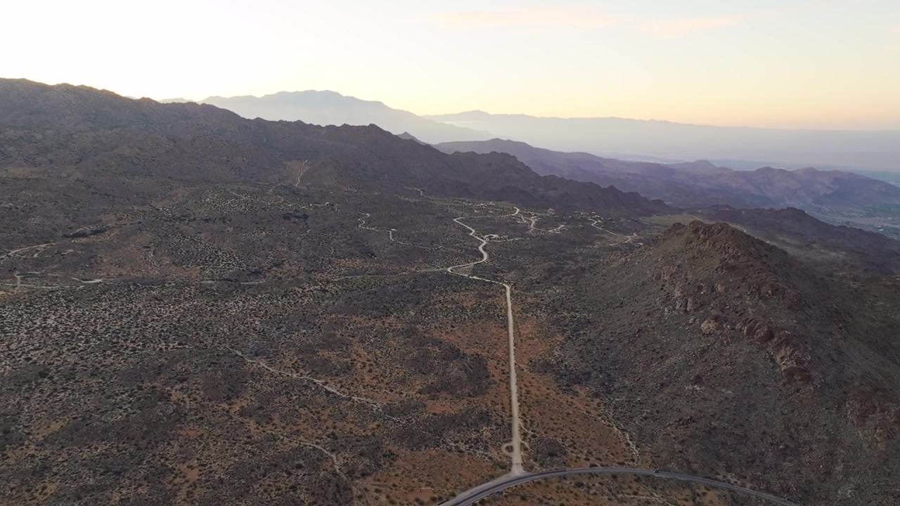 Vasto paesaggio desertico di Palm Springs con dolci colline e una catena montuosa distante, panoramica aerea con drone