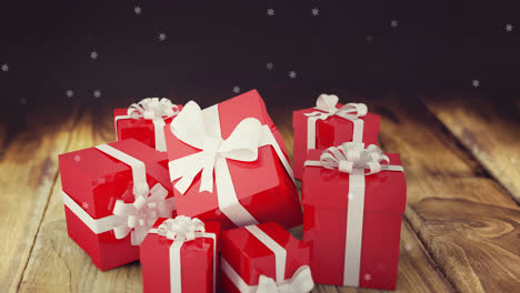 Animation-of-snow-falling-over-presents-on-wooden-background