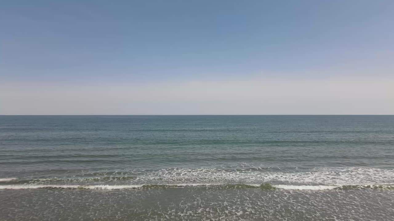 맑고 구름 한 점 없고 화창한 봄날 드론은 작은 파도를 넘어 탁 트인 대서양으로 나아갑니다.