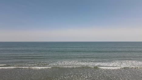 Drone-push-forward-over-small-waves-and-to-the-open-Atlantic-Ocean-on-a-clear,-cloudless-and-sunny-spring-day