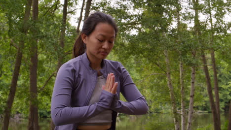 woman wearing sports clothing doing yoga in forest enjoying peace and beauty of nature