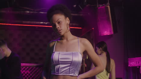 portrait of beautiful girl looking confident at camera at disco while her friends dancing behind her 5