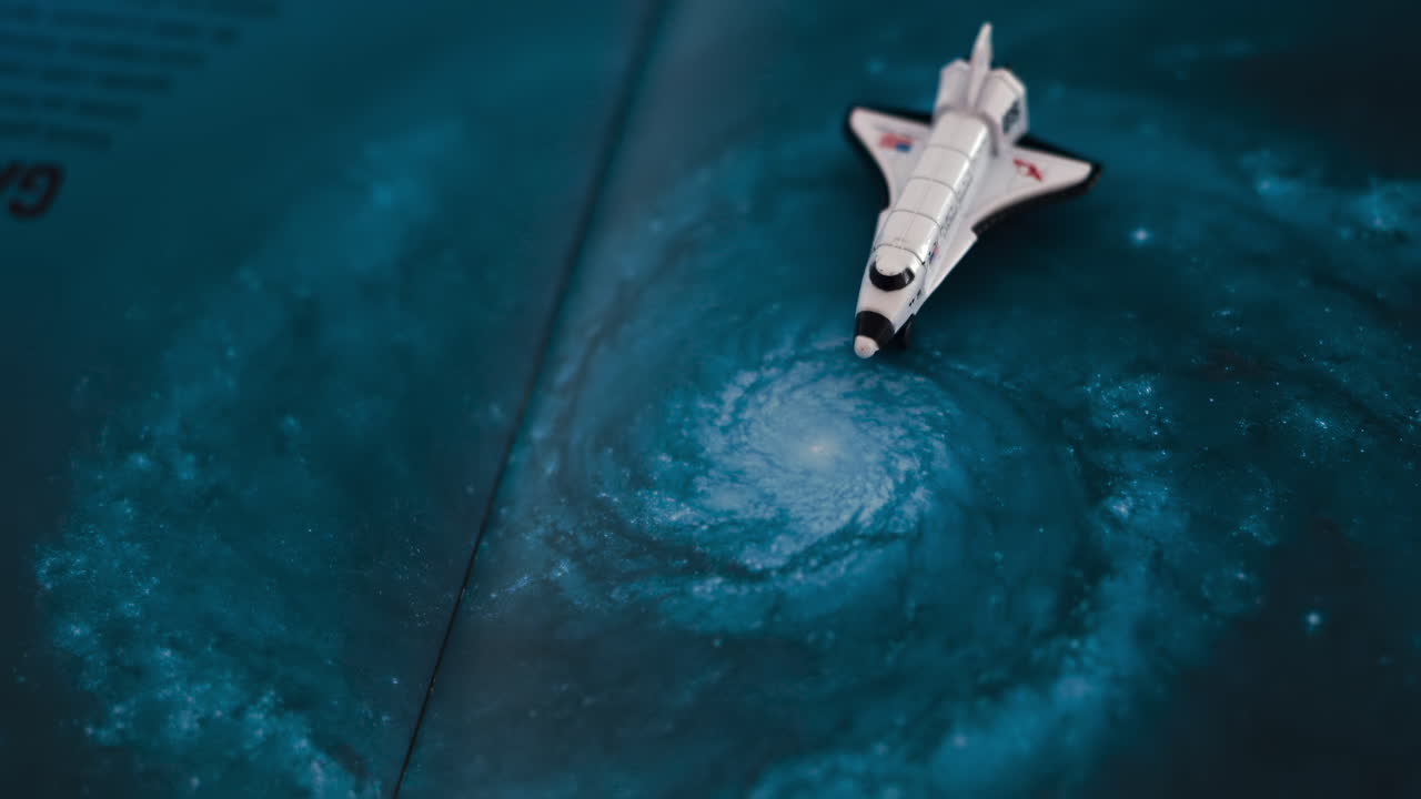 Close up of a miniature toy space shuttle placed on a blue cosmic galaxy backdrop