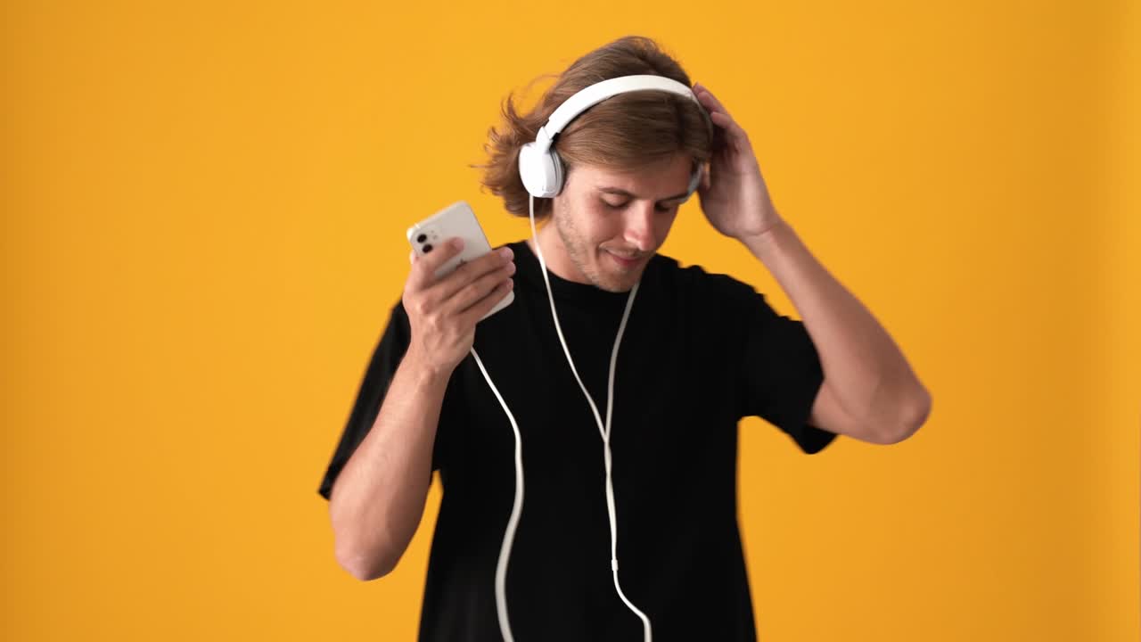 hombre positivo enviando mensajes de texto por teléfono y escuchando música