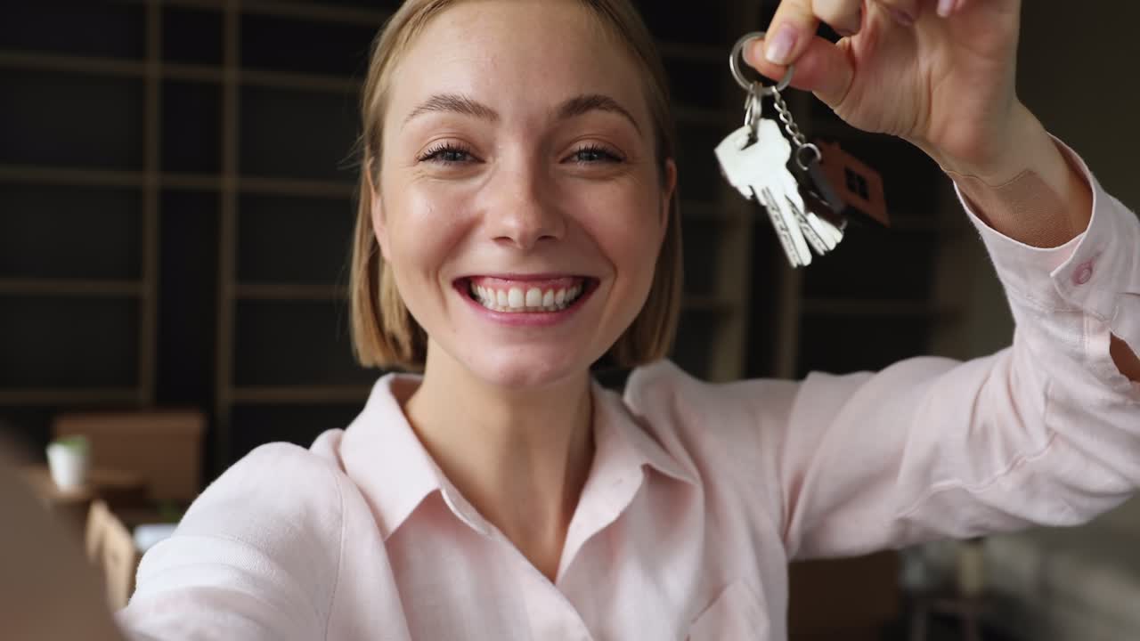 Happy woman showing keys from new home, closeup webcam view