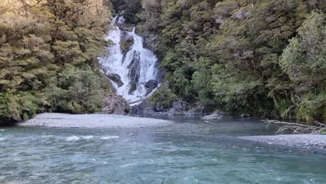 Río-Turquesa-Que-Fluye-Con-Una-Cascada-Escalonada-Rodeada-De-Selva-Tropical-En-La-Costa-Oeste-De-La-Isla-Sur,-Nueva-Zelanda