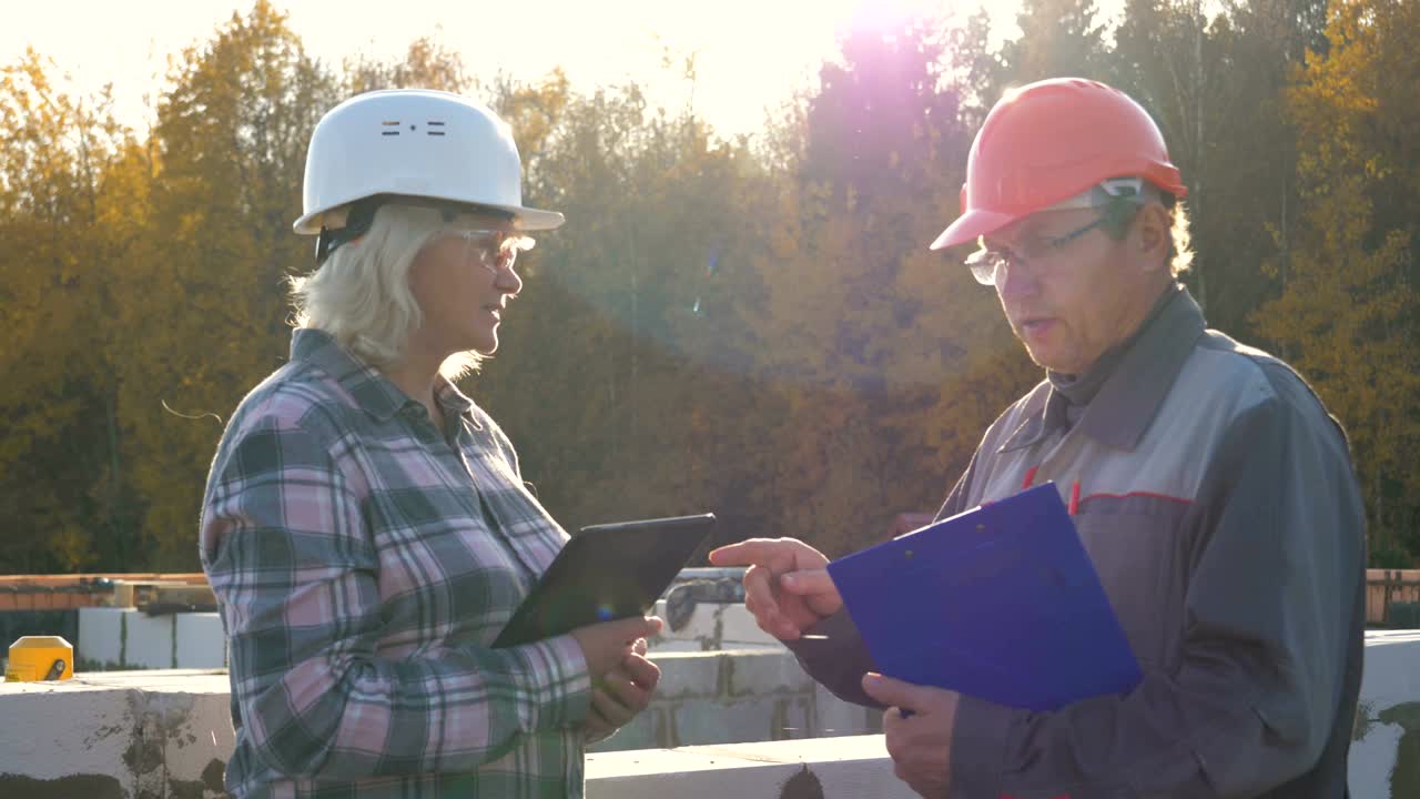 constructor y capataz en casco y gafas de protección de pie en la construcción contra el sol