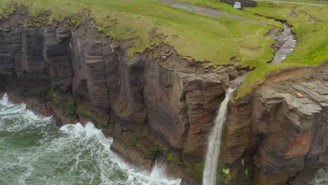 aerial static shot of a cliff edge with a waterfall in the west of ireland. moher