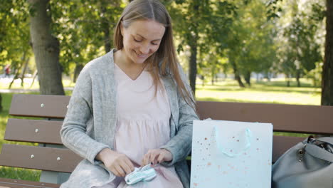 pregnant woman opens baby gift in park