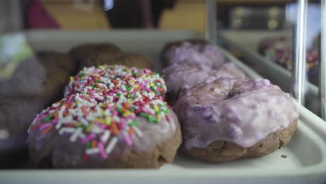 donuts con chispas y glaseado de arándanos, todo en exhibición en la tienda de donuts