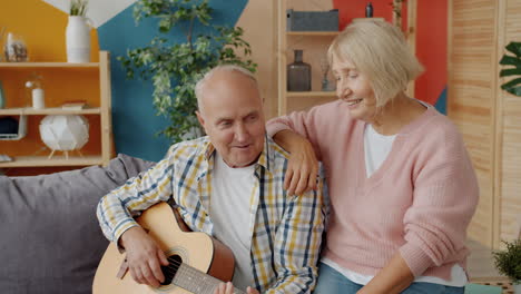 elderly couple singing and playing guitar at home
