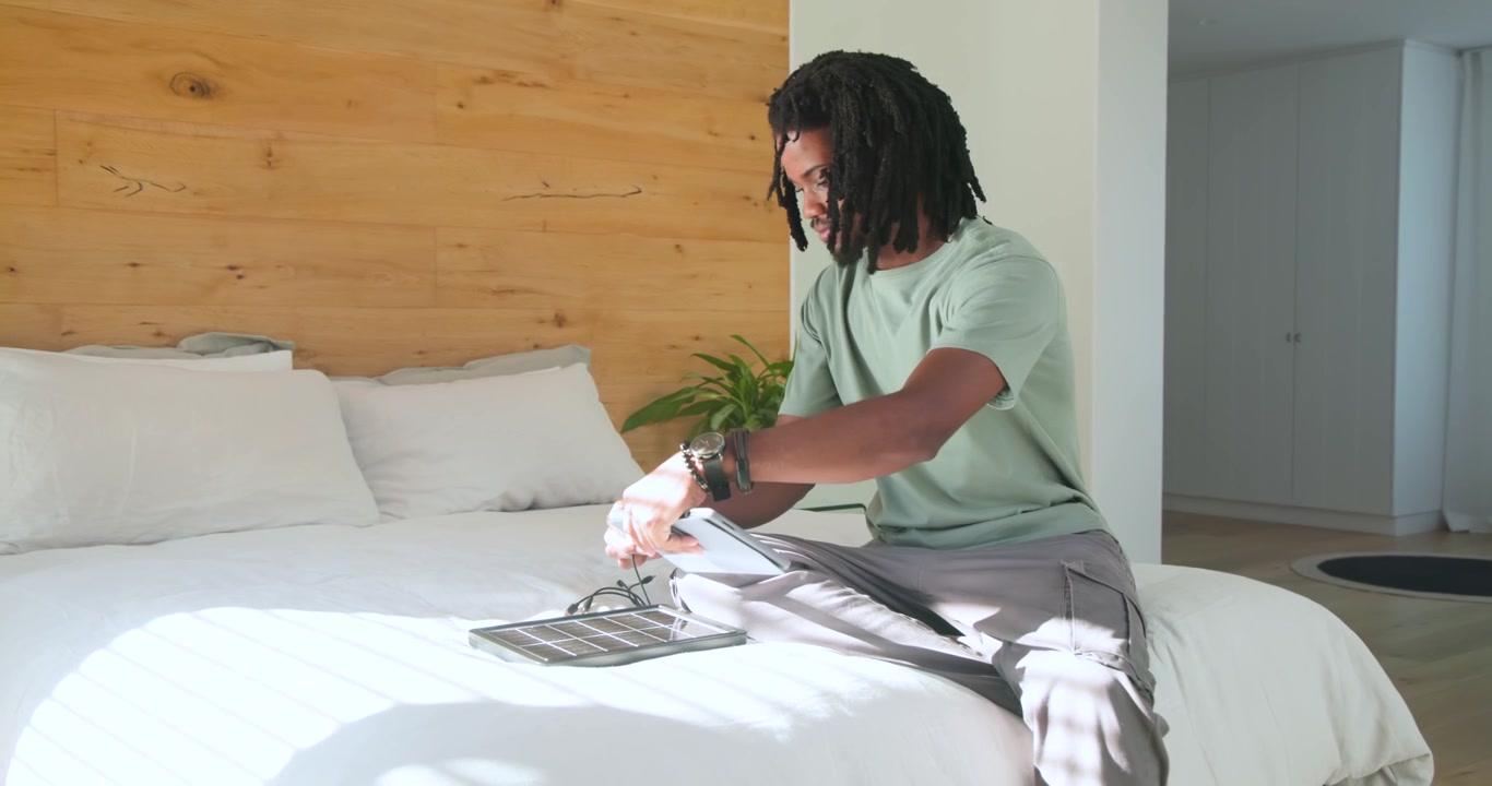 Entering bedroom with devices, man opening charger, connecting phone, charging on bed, copy space