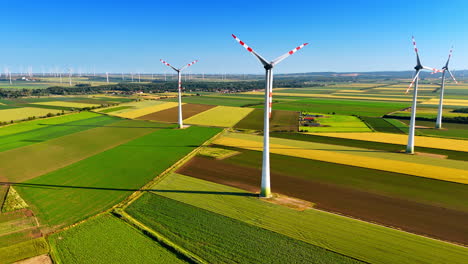 agricultural plantation of colorful patches with wind turbines installed on. aerial perspective on the wind farms producing clean energy.