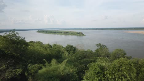 Drone-fly-out-past-pagoda-on-the-shores-of-Mekong-revealing-a-lush-island-in-the-middle-of-the-river