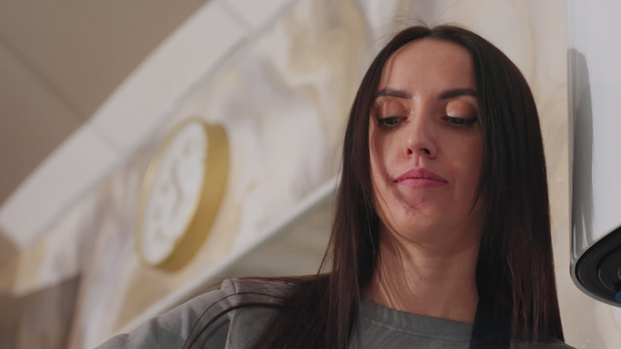 Estilista caucásica revisa las notas del cliente; profesional de la peluquería examina los detalles de la consulta con atención; estilista caucásica evalúa meticulosamente los datos de la consulta del cliente en una tablet en medio de la decoración de la peluquería