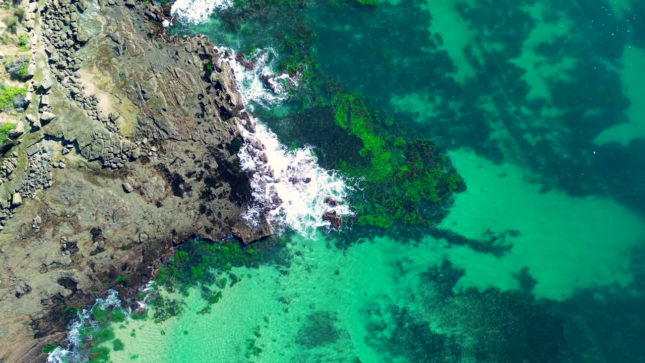 Drone aerial landscape of wave breaking along seaweed reef in ocean channel bay inlet on sandy beach coastline and rocky headland of Norah Head Central Coast Australia travel tourism diving surfing