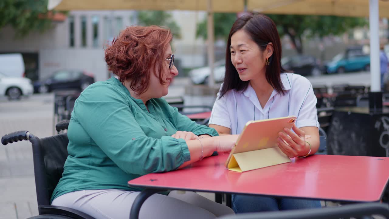 Two women having a conversation at a cafe, one in a wheelchair