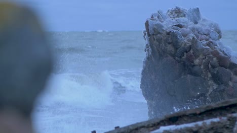 big stormy waves breaking against abandoned seaside fortification building ruins at karosta northern forts in liepaja, slow motion medium closeup