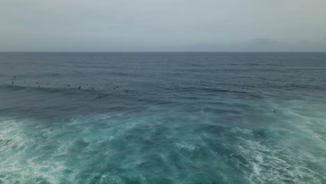 Aerial-view-of-group-of-surfers-waiting-for-big-wave-at-tropical-island-coast