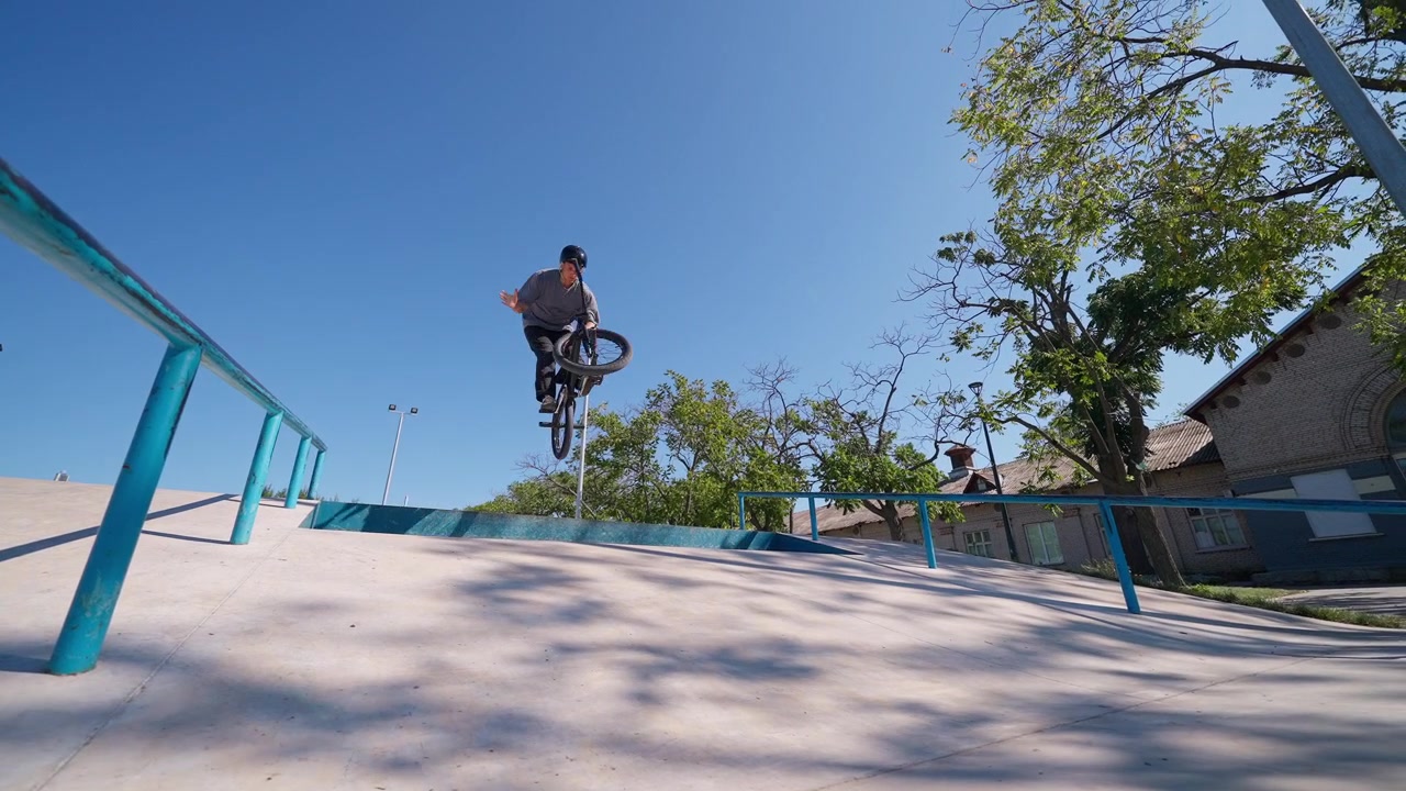 Rowerzysta BMX wykonujący trik skokowy w słonecznym skateparku na świeżym powietrzu