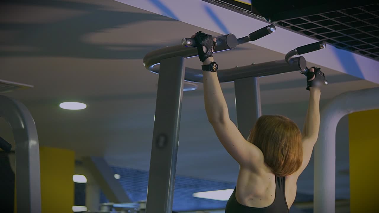 Woman Performing Pull-Ups in a Gym