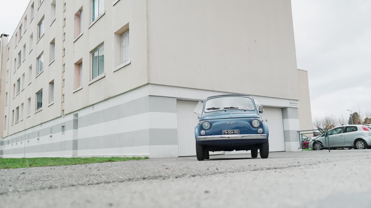 Classic Fiat 500 parked in front of apartment building