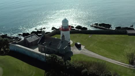 Rotating-Aerial-birds-eye-view-wide-angle-of-lighthouse-near-ocean-at-day