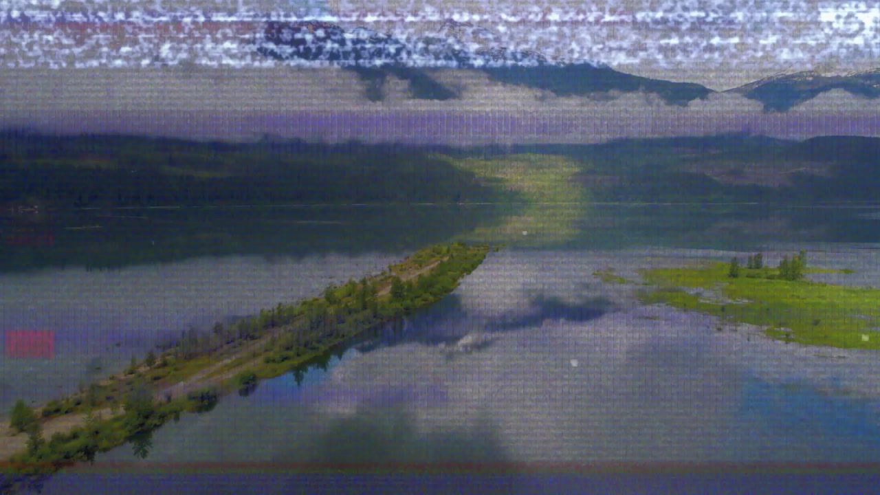 Drone feed activating and gliding along alpine lake toward peninsula capturing sunlight reflection