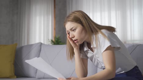 The-young-woman-who-is-unhappy-and-saddened-by-the-paper-she-is-looking-at.