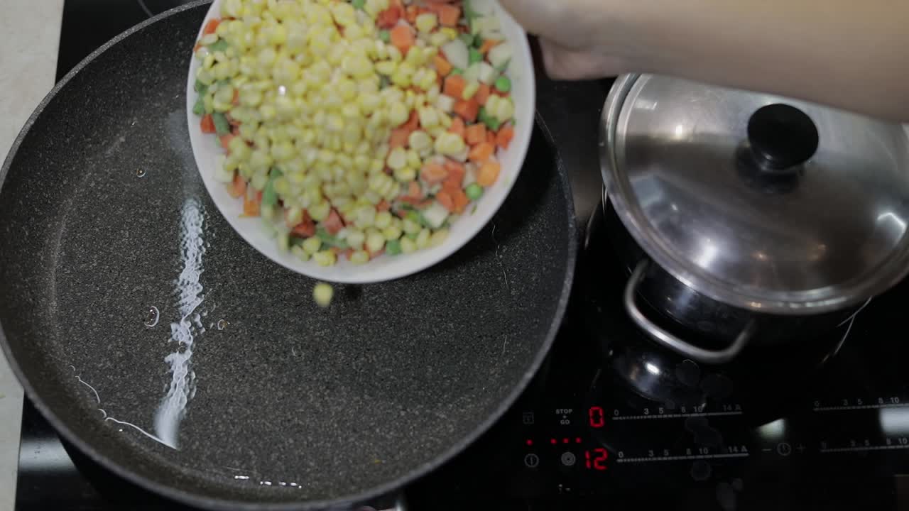 añadir verduras congeladas a una sartén caliente con aceite. guisantes, maíz, espárragos, zanahorias
