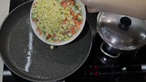 añadir verduras congeladas a una sartén caliente con aceite. guisantes, maíz, espárragos, zanahorias