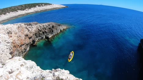 wide angle view and panoramic seascape with a kayaker exploring the coast line on a beautiful sunny day, vis island, adriatic sea, croatia