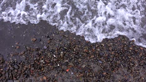 sobre rocas de colores naturales en la playa con olas rodando, cámara lenta