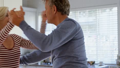 vista lateral de una pareja caucásica madura bailando juntos en la cocina en casa 4k