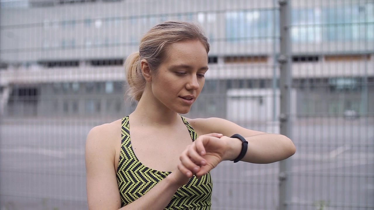 Young Woman Checking Fitness Tracker on Her Wrist Outdoors