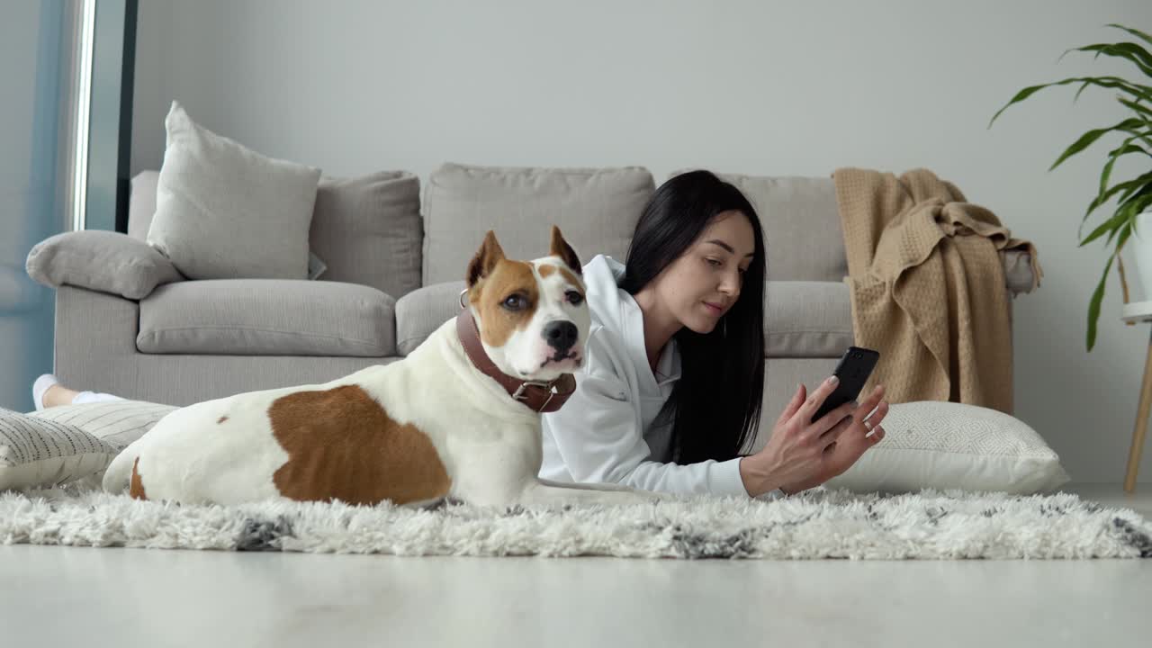 Young woman relaxing with her dog and use phone in a beautiful modern apartment