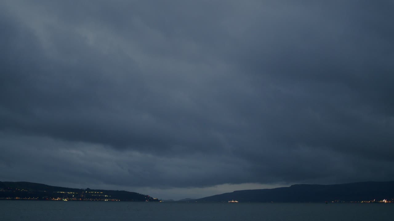 만 위의 폭풍우 구름과 함께 저녁부터 밤까지의 타임 스