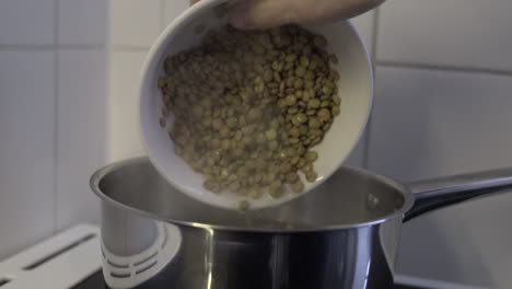 slow motion as lentil slipping in hot boiling water in a pot from a bowl