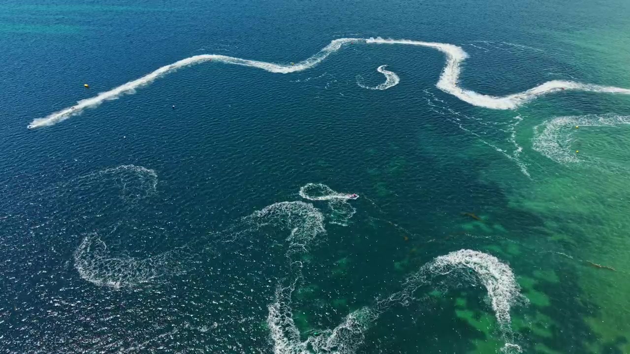 Corrida de jet ski acontece em águas claras perto de uma área costeira em um dia ensolarado