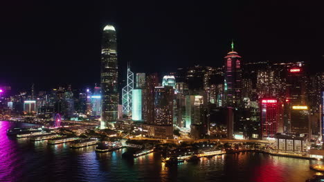 aerial drone, hong kong skyline at night of central financial district. side panning left to right, revealing buildings