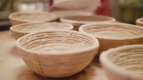 bakery powdering flour over ferment baskets