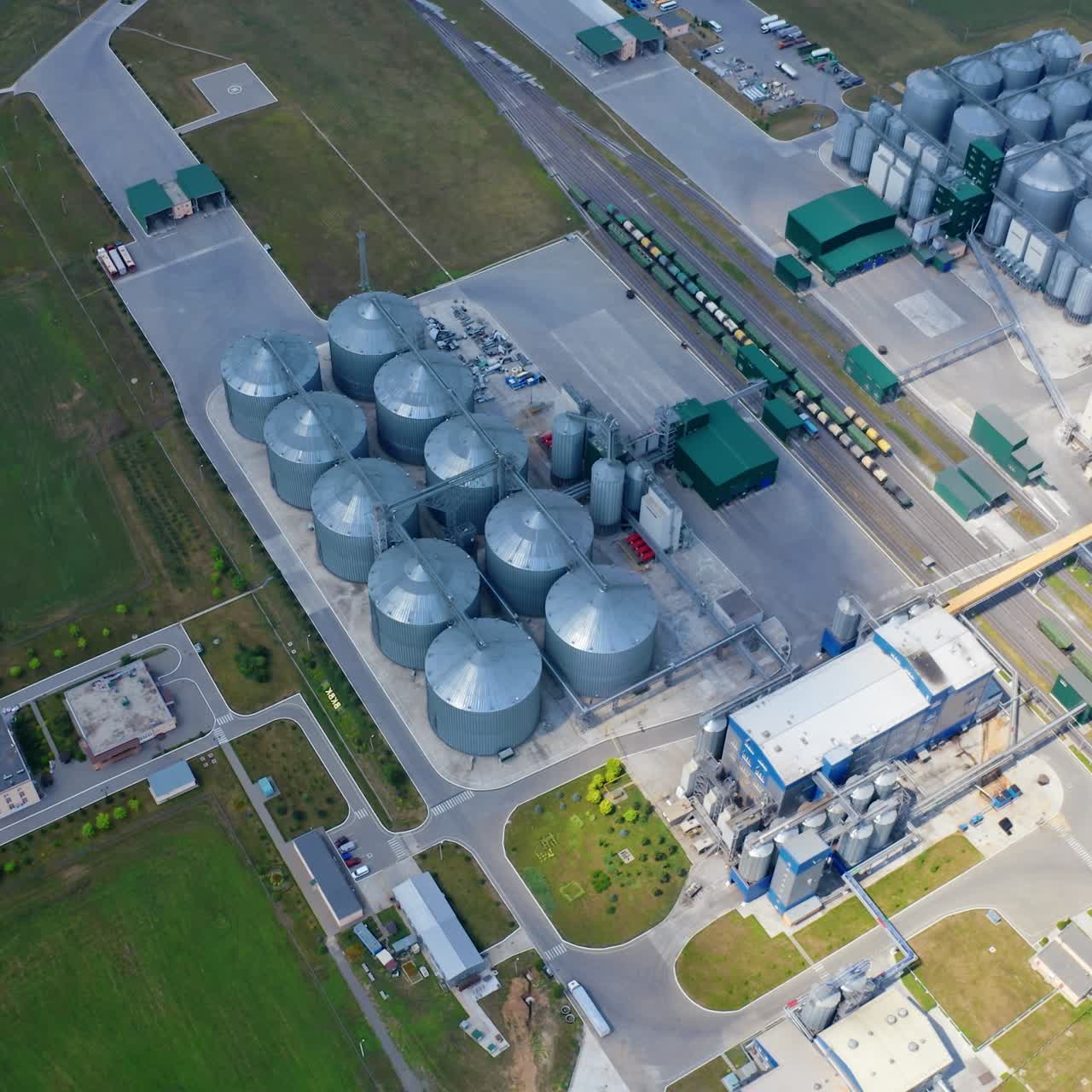 Grain elevators on field. Modern plant for agricultural business. Large metal silos of grain-drying complex. Top aerial view