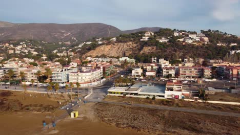 castelldefels beach in barcelona, with long sandy shore, palm trees, and urban backdrop, early morning light, aerial view