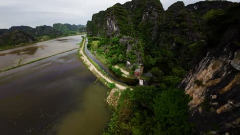 el dron fpv se desliza sobre los campos de arroz inundados en tamcoc, vietnam, reflejando el cielo nublado.