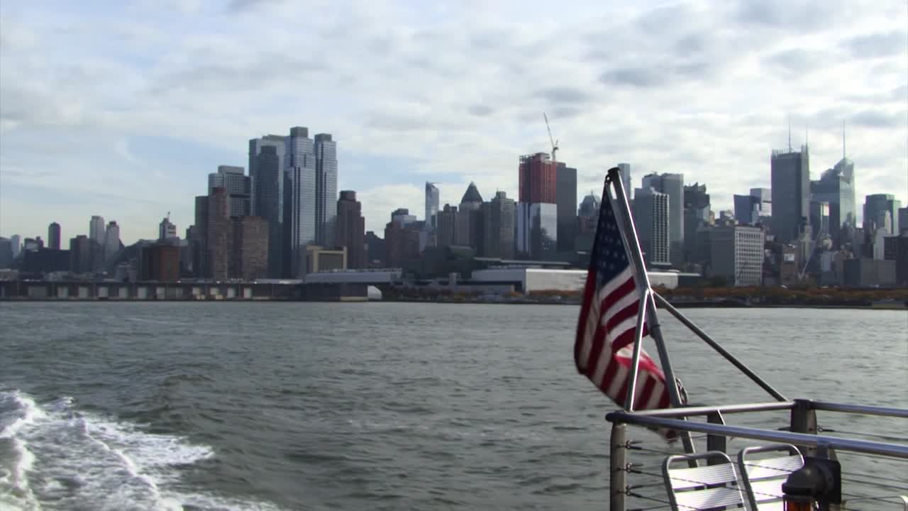 Lo skyline di Downtown Manhattan dal tour in traghetto e la bandiera USA