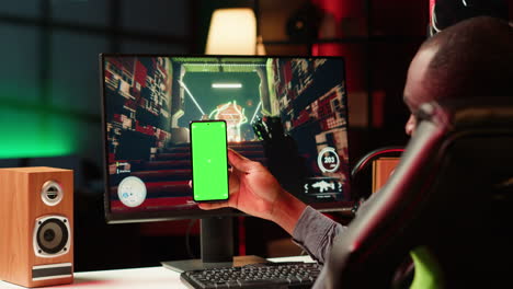 hombre enviando mensajes de texto a amigos en el teléfono de pantalla verde mientras juega un juego