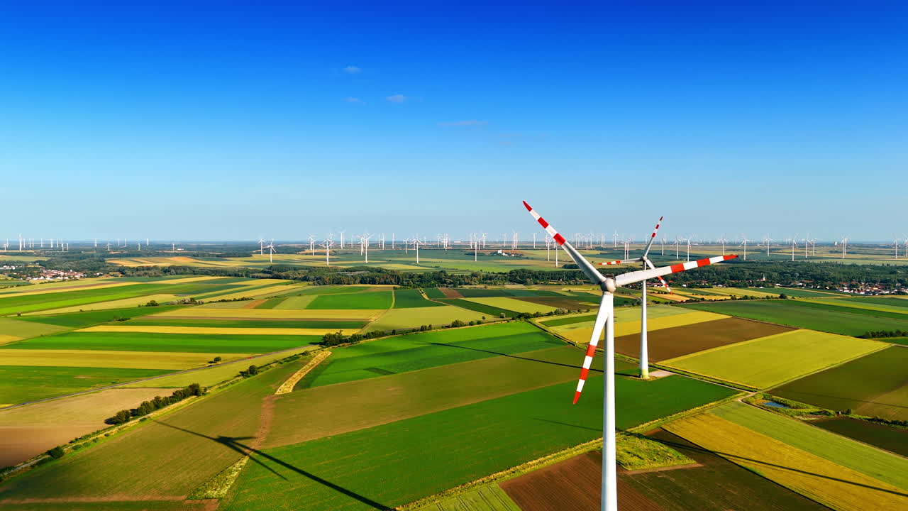 Turbines on green hills under blue. A view features multiple wind turbines against a backdrop of vibrant green fields and a clear blue sky